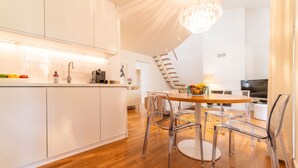 Una cocina moderna con armarios blancos, una mesa de comedor de madera con sillas y una araña.