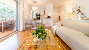 Una sala moderna con un sofá, una mesa baja con una planta, y un comedor con una mesa y sillas.