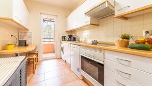 A compact kitchen with a washing machine, a coffee maker, and a sink.