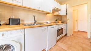 A modern kitchen with white cabinetry, a dishwasher, an oven, and a sink.