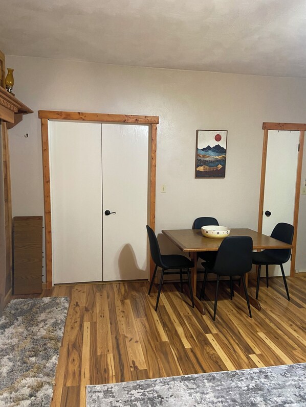 A dining area with a wooden table and chairs, a white door, and a painting on the wall. - Fall in the Laurel Highlands! (Champion)