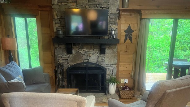 A cozy living room with a stone fireplace, comfortable seating, and a television. - Pool open beyond Labor Day! Enjoy the quiet! (Champion)