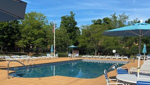 A pool area with lounge chairs and umbrellas, surrounded by a fence and trees. - Pool open beyond Labor Day! Enjoy the quiet! (Champion)