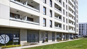 A modern multi-story building with a flat facade, large windows, and balconies. - Ursus Habicha (Warsaw)