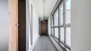 A long, narrow hallway with large windows on one side and a wooden door on the other. - Ursus Habicha (Warsaw)