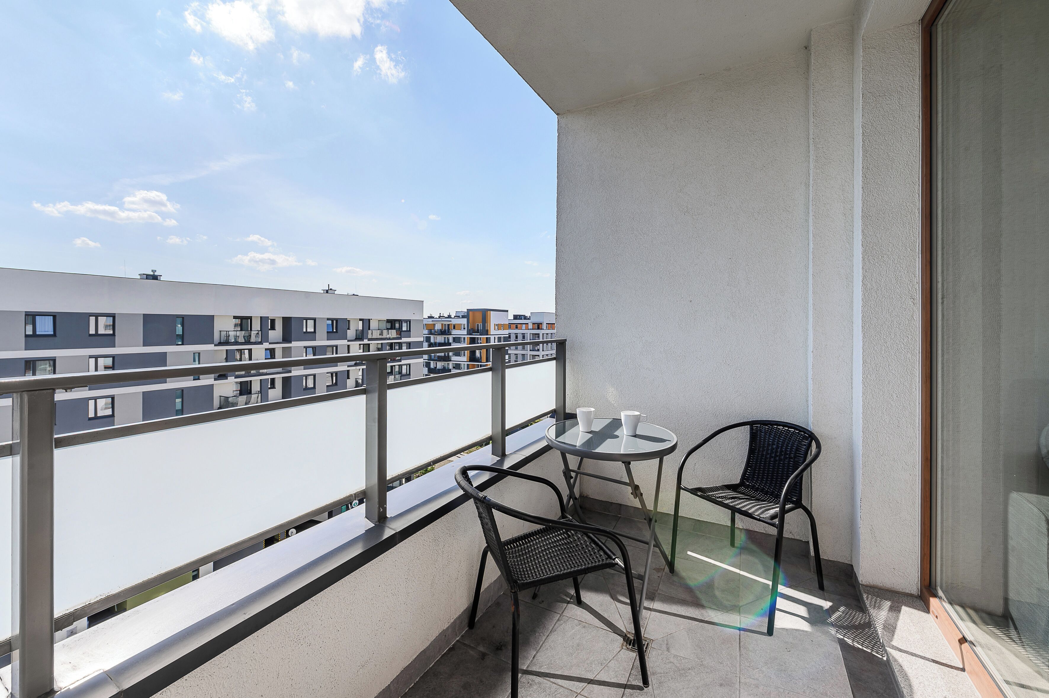 Un balcón con una mesa y dos sillas, con vista a un paisaje urbano.