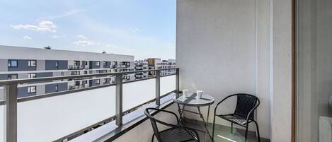 Un balcón con una mesa y dos sillas, con vista a un paisaje urbano.