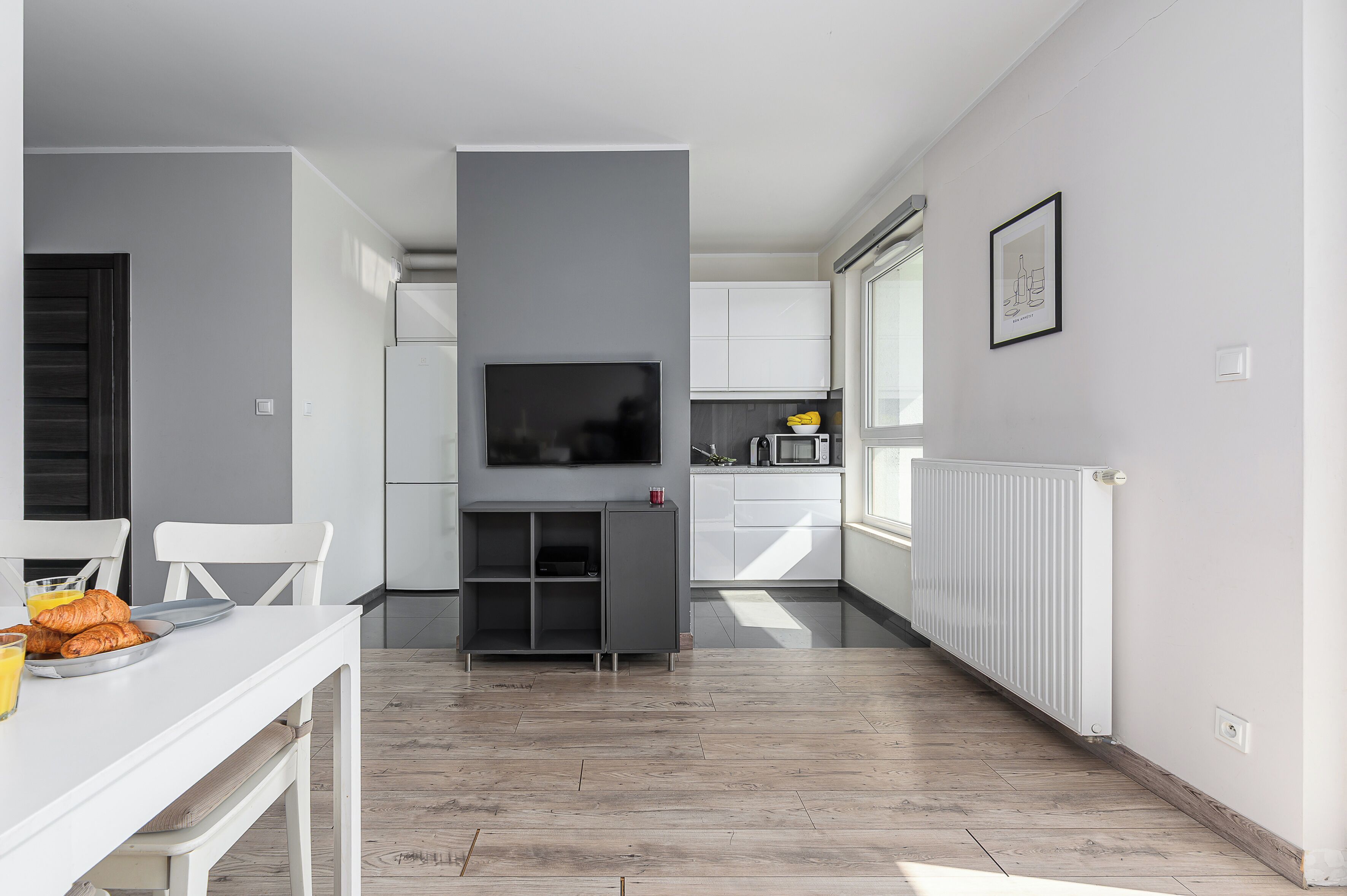 A modern kitchen with white cabinets, a built-in oven, and a microwave.