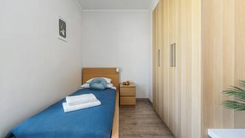 Una camera da letto piccola e ordinata con un letto singolo, un comodino, un armadio e un quadro appeso alla parete.