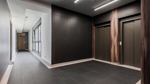 A modern hallway with dark walls, large windows, and a tiled floor. - Ursus Habicha (Warsaw)