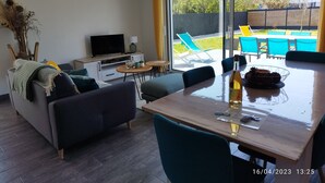 Un salon moderne avec un téléviseur, un canapé, une table à manger et des chaises.