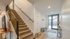 A modern interior with a wooden staircase, a bench, a small table, and a door leading to a glass door. - Long stays|Desk|Garage (Salt Lake City)