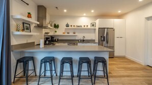 A modern kitchen with a central island, bar stools, white cabinetry, and stainless steel appliances. - Long stays|Desk|Garage (Salt Lake City)