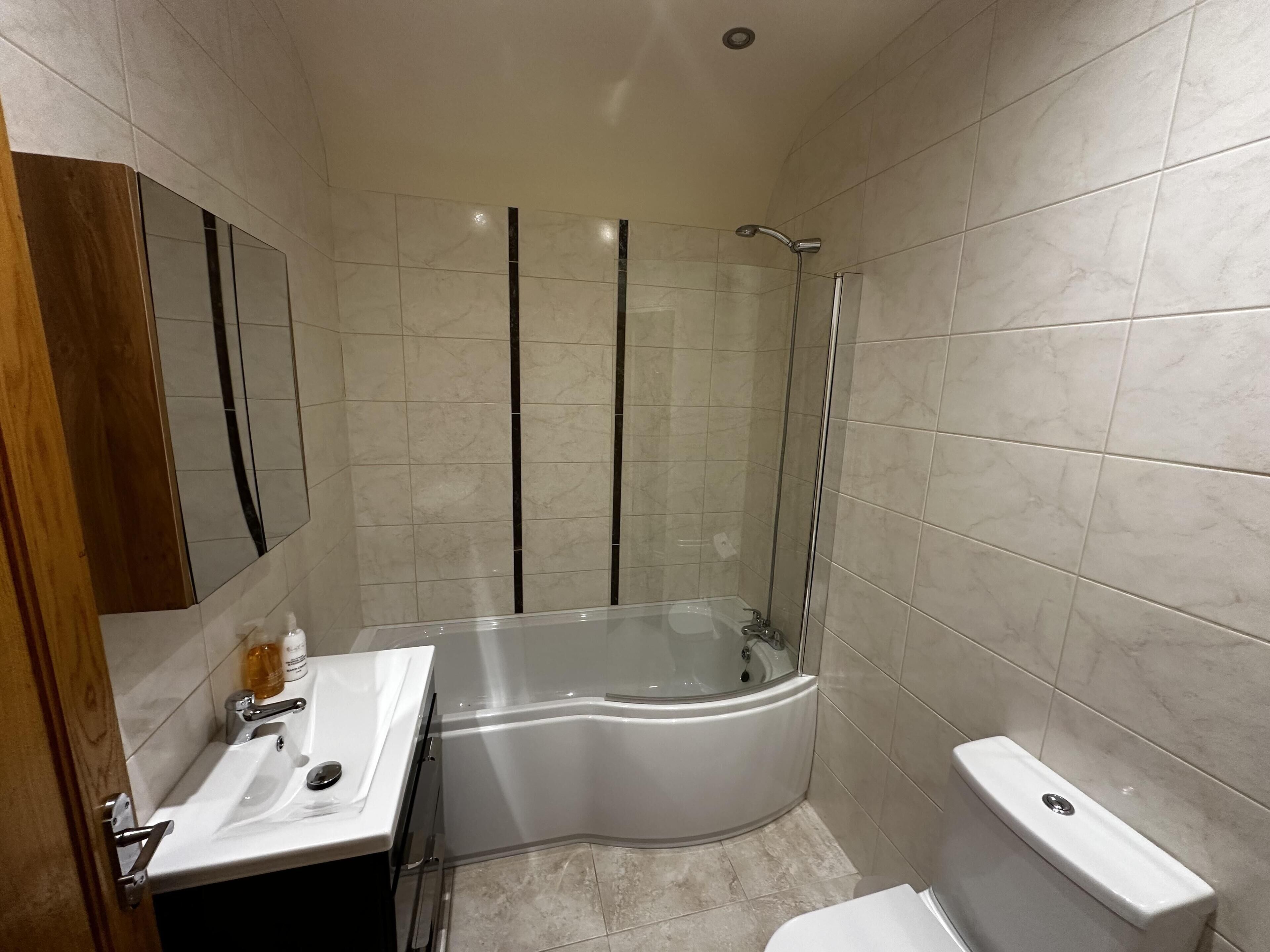 Un baño moderno con ducha de vidrio, un lavabo blanco y un inodoro.