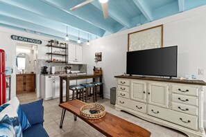 A compact living space with a kitchenette, a dining area, a sofa, and a television.