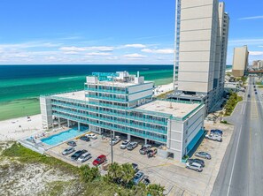 A hotel with a pool, parking, and a view of the ocean.