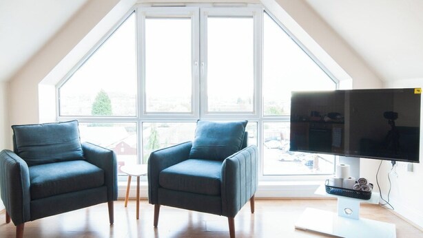 A room with two armchairs, a television, and a large window with a view of buildings and trees. - Caribou Suite-Bright & Spacious 2-Bed | Gated Parking | Close to City & Hospital (Burton upon Trent)