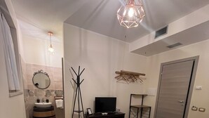 A modern bedroom with a large bed, a TV, and a coat rack. - B&B VILLA VERONA BIKE (Buttapietra)