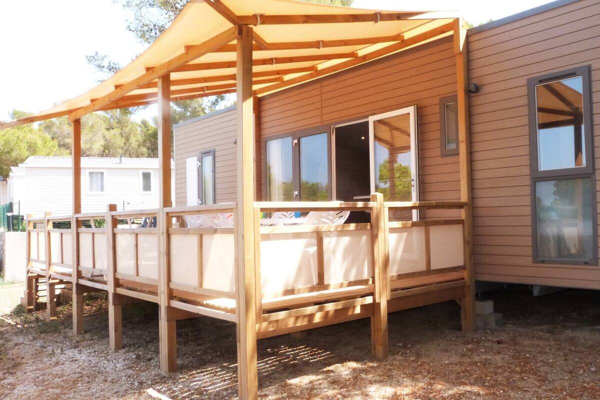 Una estructura de madera con un porche cubierto, ventanas grandes y un suelo de grava.