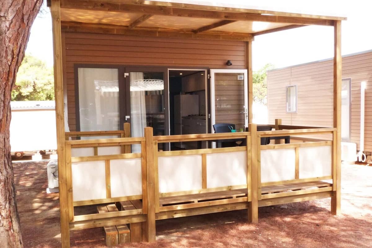 Una estructura de madera con un porche cubierto, una ventana y una puerta.