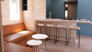 Eine moderne Küche mit Barbereich, einer Sitzecke mit Sofa und Barhocker sowie einem großen Fenster für natürliches Licht.