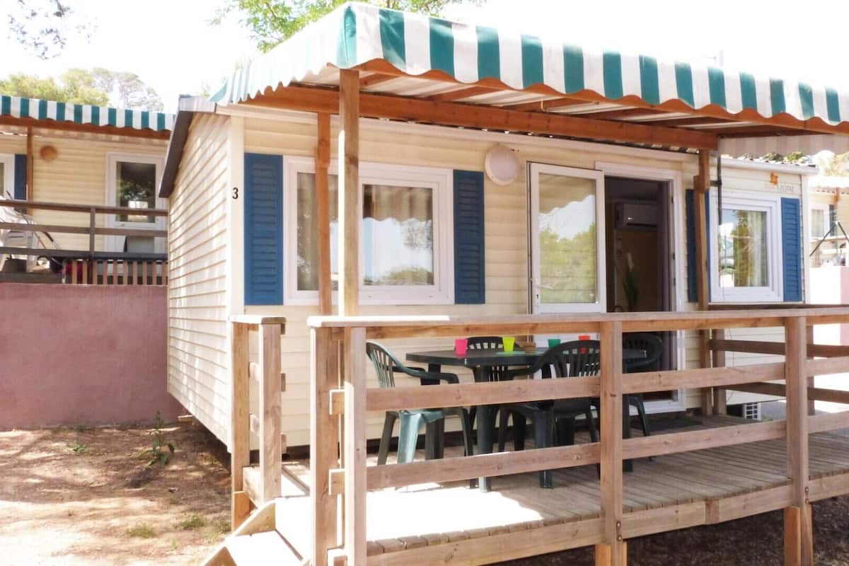 Una casa móvil con terraza de madera y un porche cubierto.
