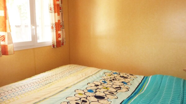 Una habitación con una cama individual, una ventana con cortinas y una pared sencilla.