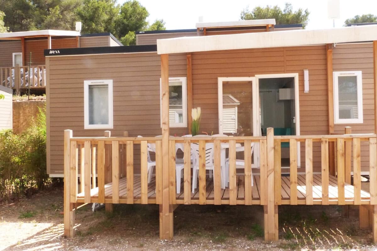 Una casa móvil de madera con un porche, dos ventanas y una puerta.