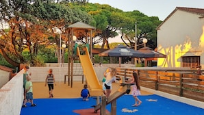 Ein Spielplatz mit Rutsche, Klettergerüst und einem Netzbereich.
