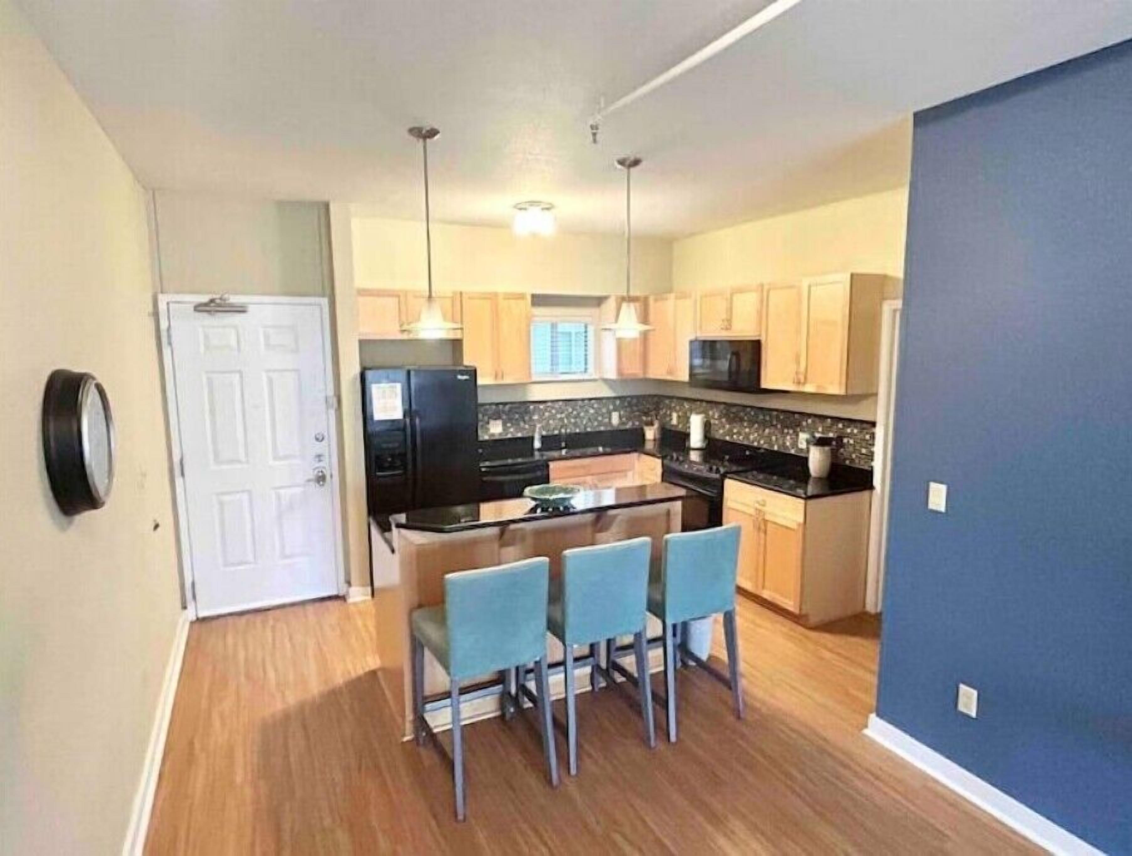 A compact kitchen with a central island, a dining area with four chairs, and a microwave above the island.