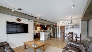 Een moderne woonkamer met een leren bank, een houten salontafel en een flatscreen televisie aan de muur.
