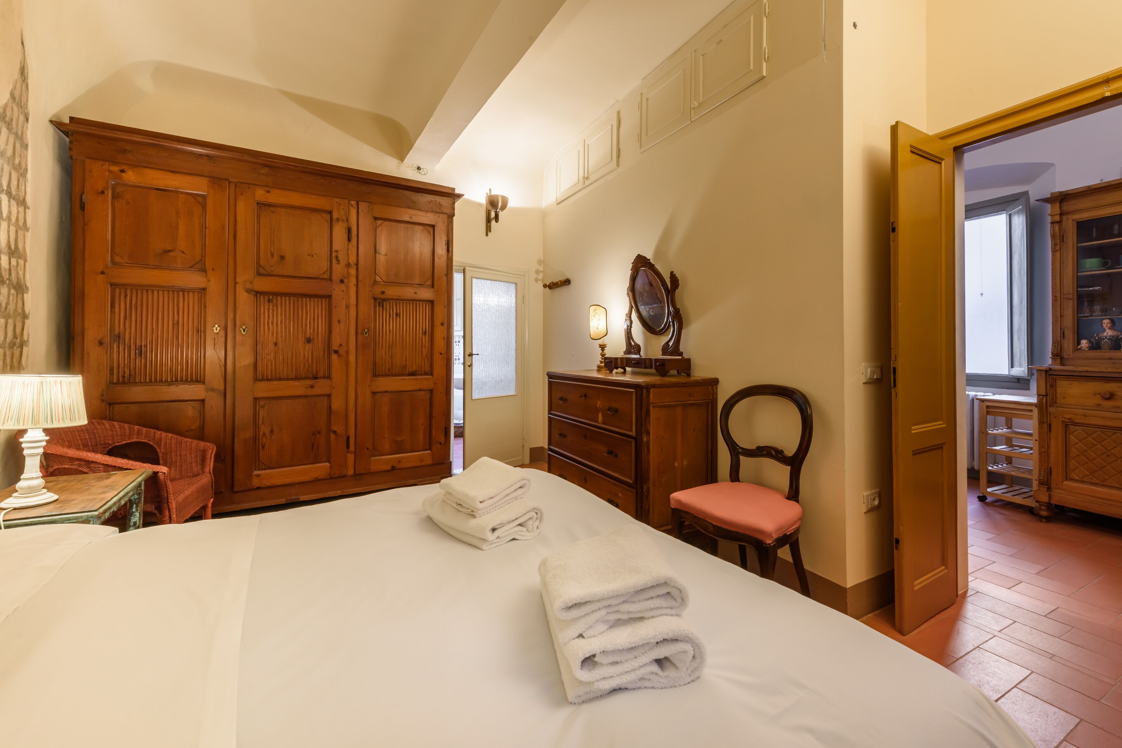 Un dormitorio con una cama grande, un armario de madera y una silla.