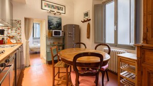 A compact kitchen with a dining table, chairs, a microwave, and a radiator. - Casa torre via de' Neri by Mmega (Florence)
