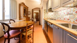 A kitchen with a wooden dining table, chairs, and a built-in oven. - Casa torre via de' Neri by Mmega (Florence)