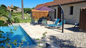 Un jardin avec une piscine, du mobilier d’extérieur et un bâtiment en pierre.