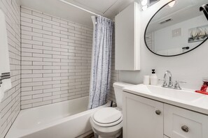 Ein modernes Badezimmer mit einer weißen Badewanne, einer weißen Toilette und einem Waschbecken mit Spiegel darüber.