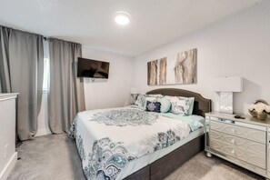 Ein Schlafzimmer mit Bett, Fernseher, Gemälde und Kommode.