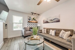 Ein stilvolles Wohnzimmer mit einer Couch, einem Sessel und einem Glastisch.
