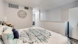 Ett sovrum med en säng, ett sängbord med en lampa, en rund väggdekoration och en garderob.