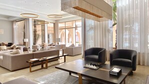 A spacious living room with a large sofa, two armchairs, a coffee table, and a chess set.