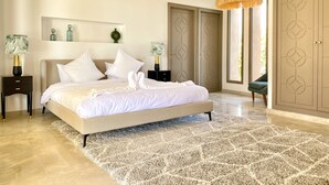 A spacious bedroom with a large bed, two nightstands, a decorative rug, and a view of the outdoors through a door.