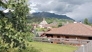 Ein ländliches Dorf mit traditionellen Gebäuden, einer Kirche und Bergen im Hintergrund.