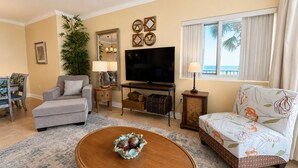 A living room with a sofa, armchair, television, and decorative items.