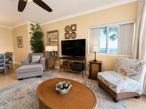 A living room with a sofa, armchair, television, and decorative items.