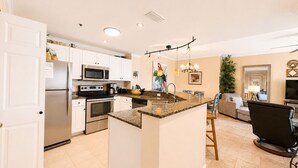 A modern kitchen with white cabinets, stainless steel appliances, and a granite island.