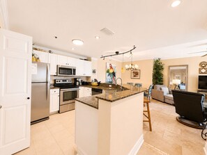 A modern kitchen with white cabinets, stainless steel appliances, and a granite island.