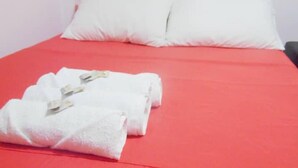 A bed with a red bedspread, white pillows, and two neatly folded white towels. - Central and Private 1km From the Hacienda Naples (Antioquia)