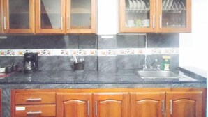 A kitchen with wooden cabinets, a black countertop, and a tiled backsplash. - Central and Private 1km From the Hacienda Naples (Antioquia)