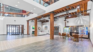 A spacious lobby with a high ceiling, wooden beams, and a modern reception desk. - Riverfront Loft - Arch Views - Onsite Fitness Center (St. Louis)