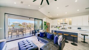 A modern kitchen with white cabinets, a central island, and bar stools.